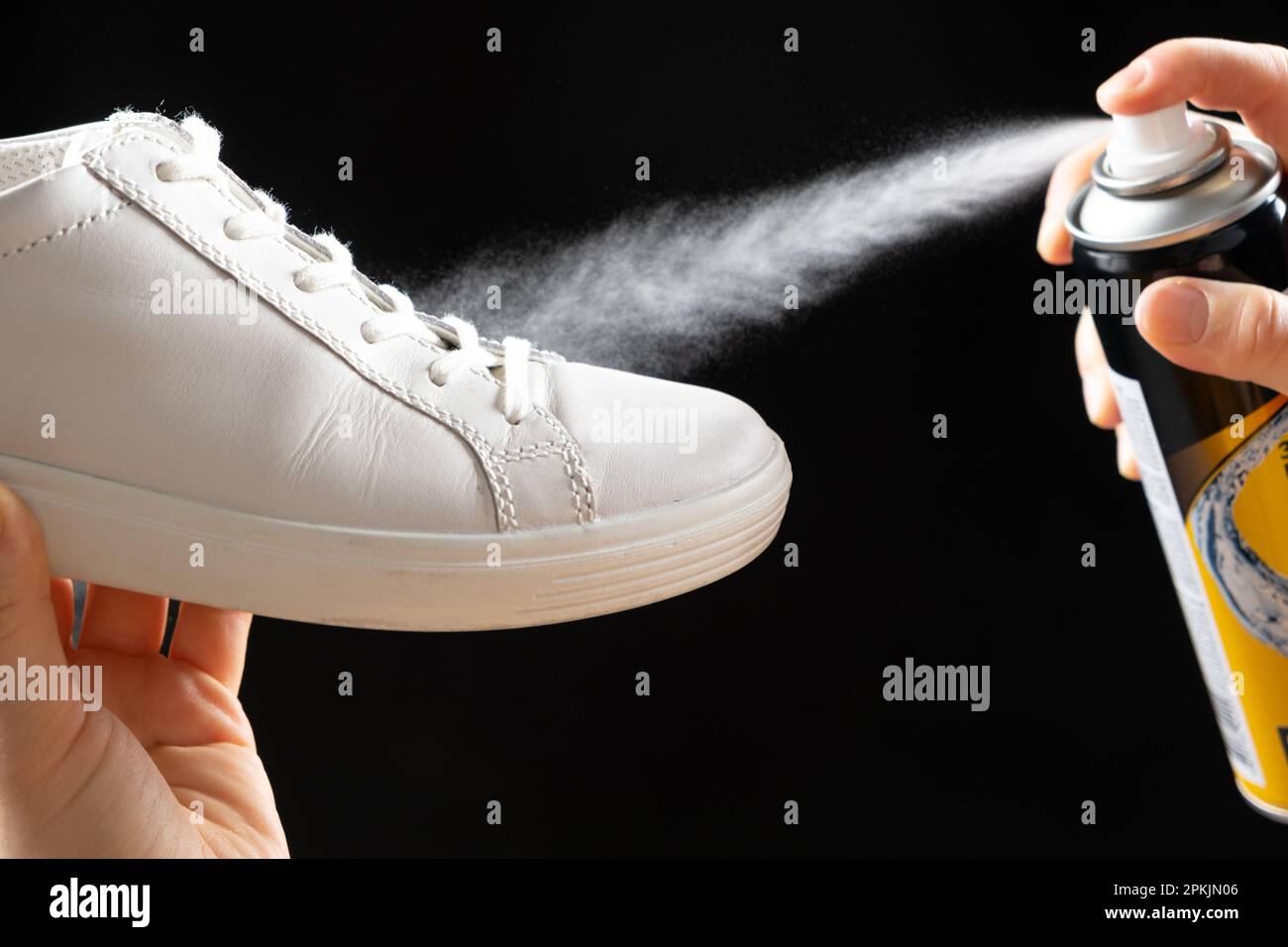 Applying a water-repellent hydrophobic spray to white women's sneakers.  Protection of shoes from moisture, dirt and unpleasant odor Stock Photo -  Alamy