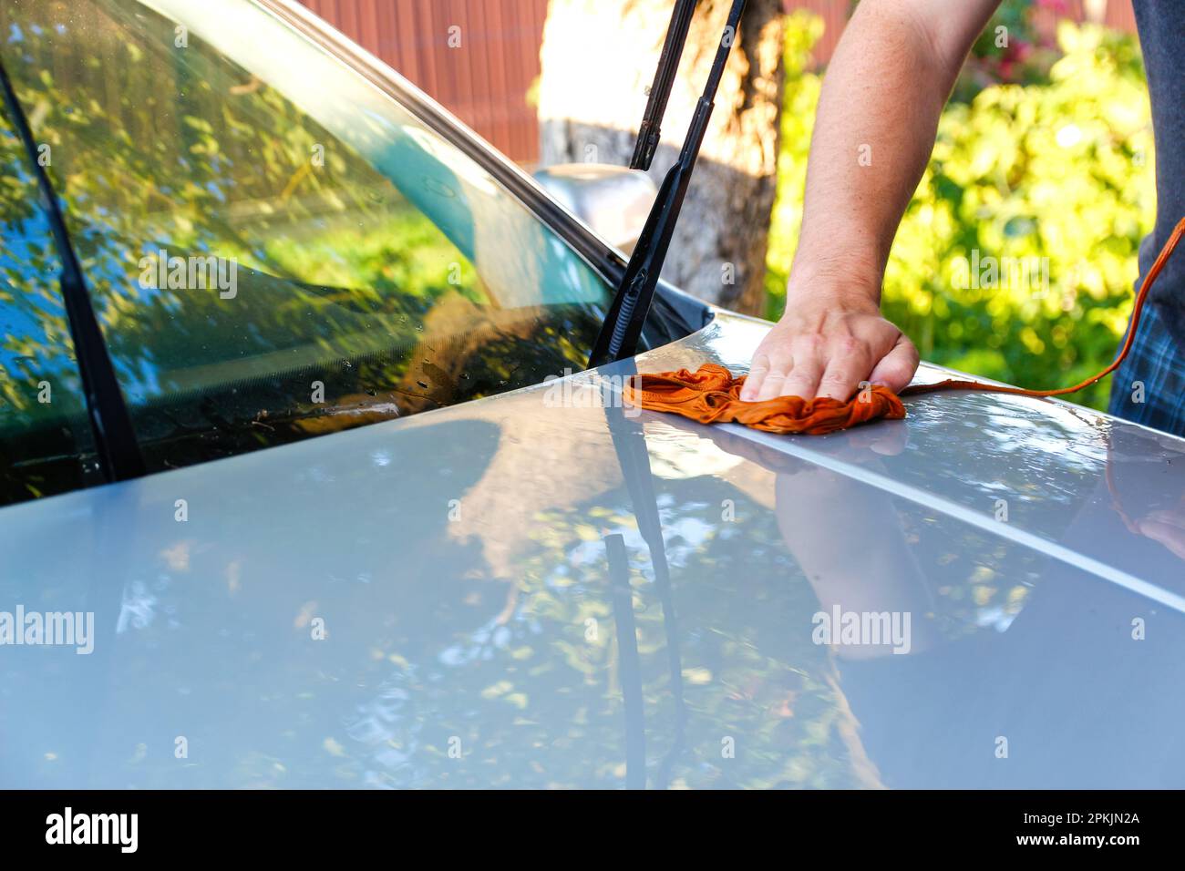 Man washing gray car with sponge wash. Man holds the microfiber in hand and polishes the car. detailing series, worker cleaning gray car. Out of focus Stock Photo