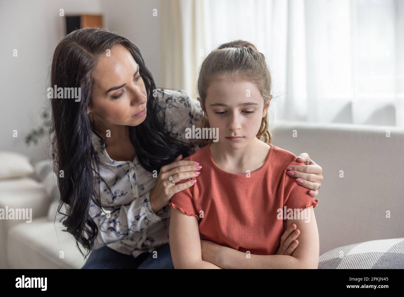 Mother Comforts Upset Daughter That Sits With Arms Crossed On A Couch