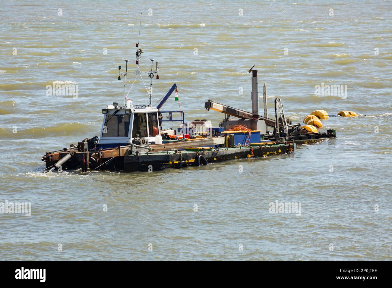 A dredging boat at work in West Bay harbour removing sand and sediment that has accumulated over the winter. West Bay Dorset England UK GB Stock Photo
