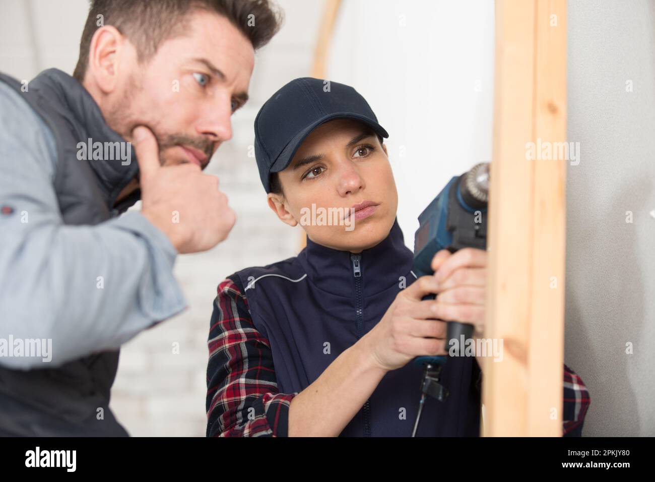 carpenter using a drill on a wood house structure Stock Photo