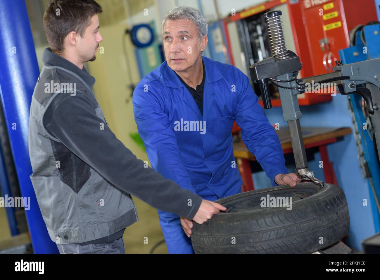 apprentice mechanic and teacher retreading wheel in automotive