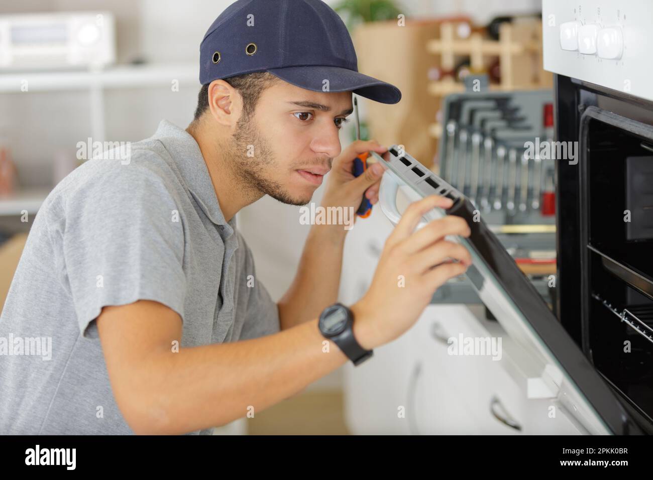 man with screwdriver in his hand fixing oven door Stock Photo Alamy