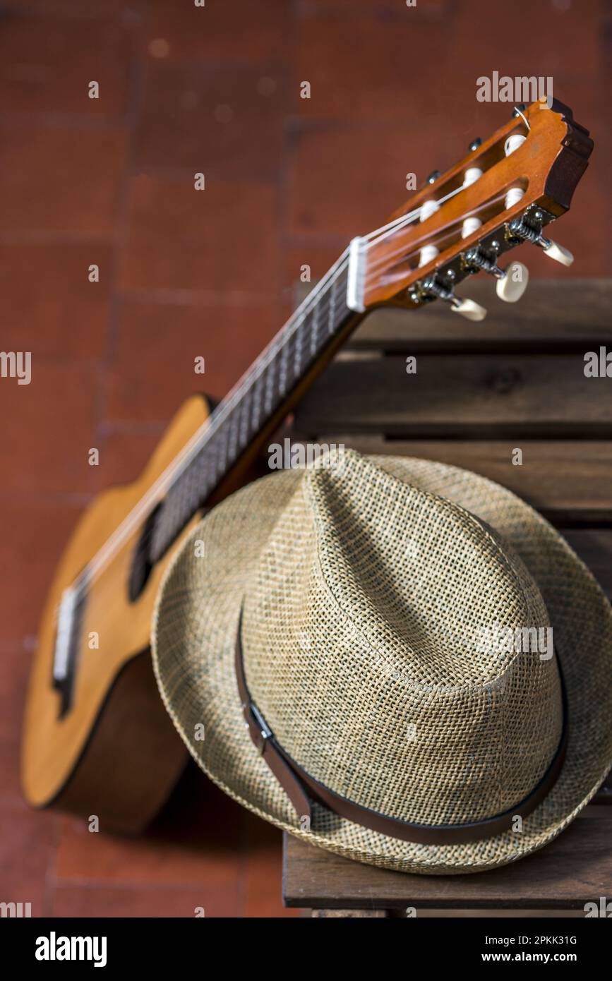 A guitar resting on a wooden box and a straw hat Stock Photo