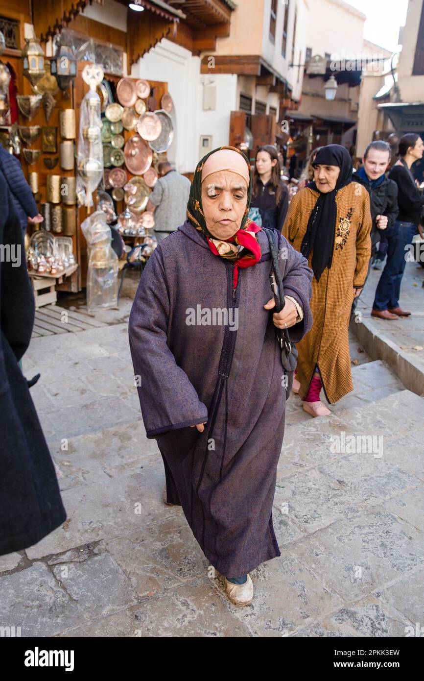 A traditionally dressed Moroccan woman walks through Fez Medina Stock Photo