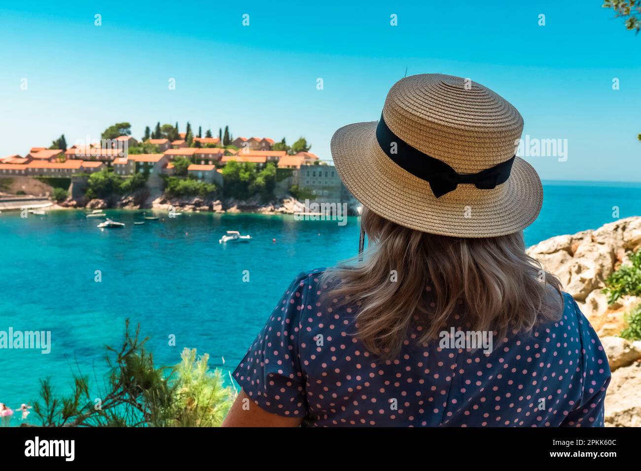 Montenegro. Adriatic Sea. Island and beach of Sveti Stefan. Sunny weather. A very popular tourist spot. Woman in a straw hat admiring a beautiful view Stock Photo