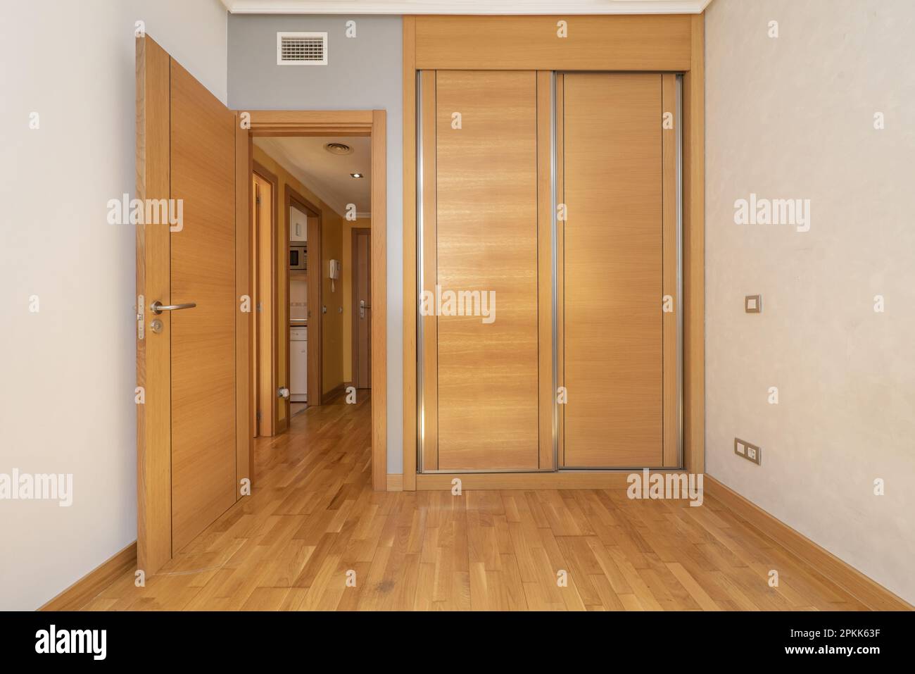 Empty room with builtin wardrobe with sliding wooden doors, ducted air