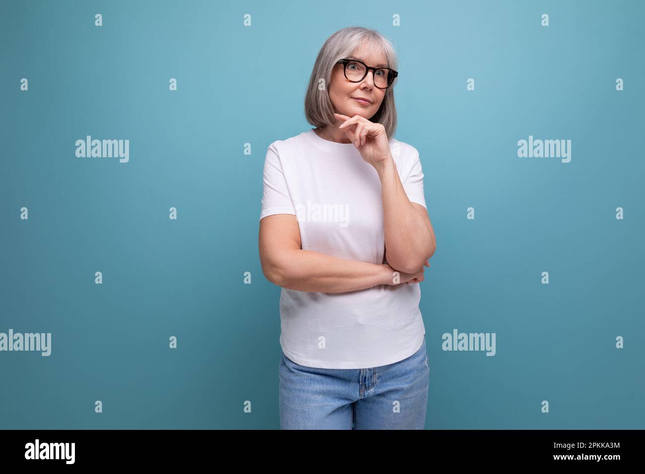 serious 60s woman pensioner in white tank top on studio background Stock Photo
