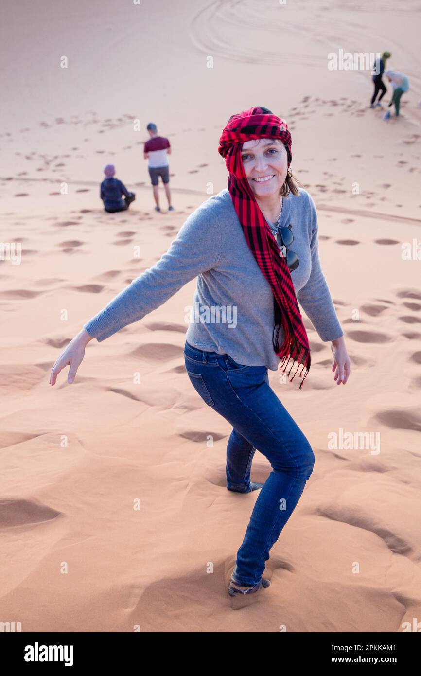 An American tourist wearing a headscarf in the sand dunes of the Sahara Desert in Merzouga Stock Photo