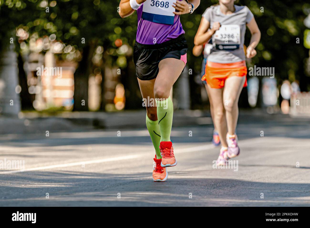 legs female runner athlete run marathon race on city street, legs woman jogger in compression socks Stock Photo