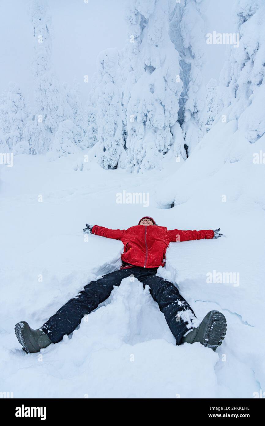Cheerful woman smiling lying down in the snow, Lapland, Finland, Europe Stock Photo