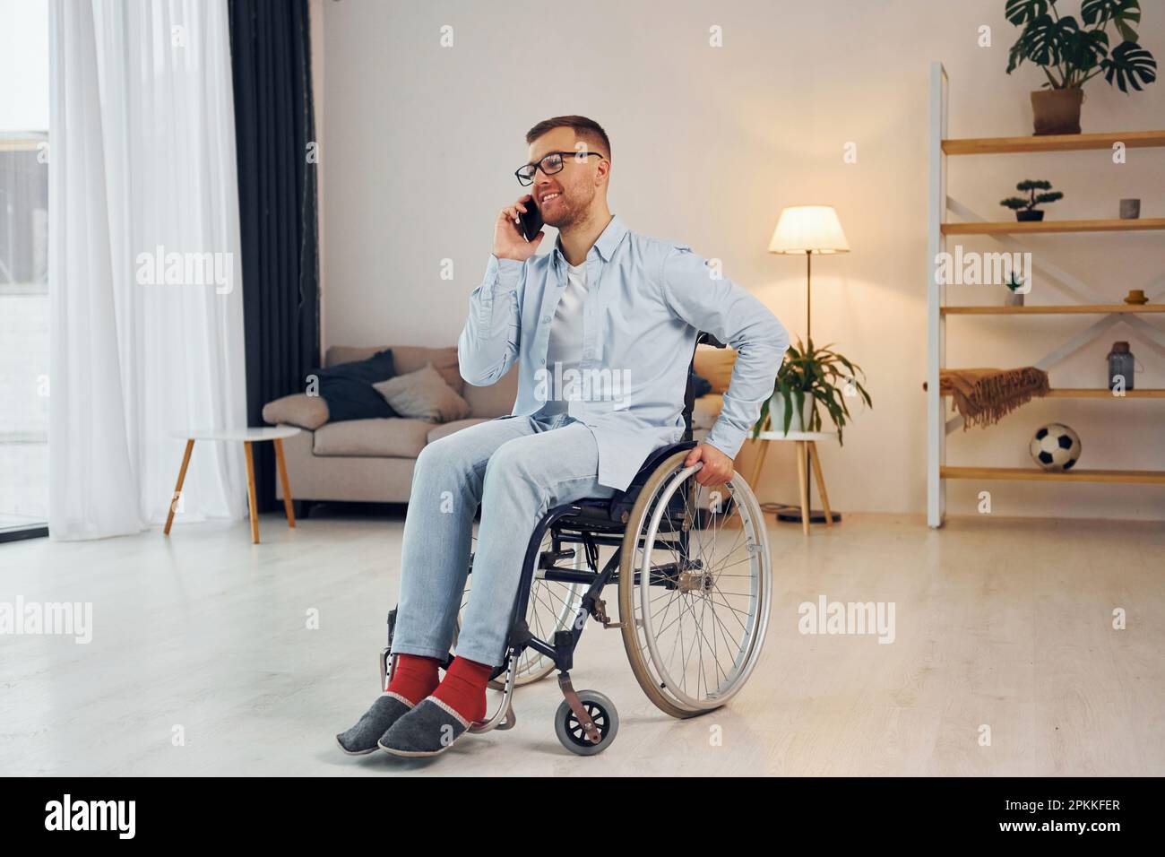 Using phone. Disabled man in wheelchair is at home Stock Photo Alamy