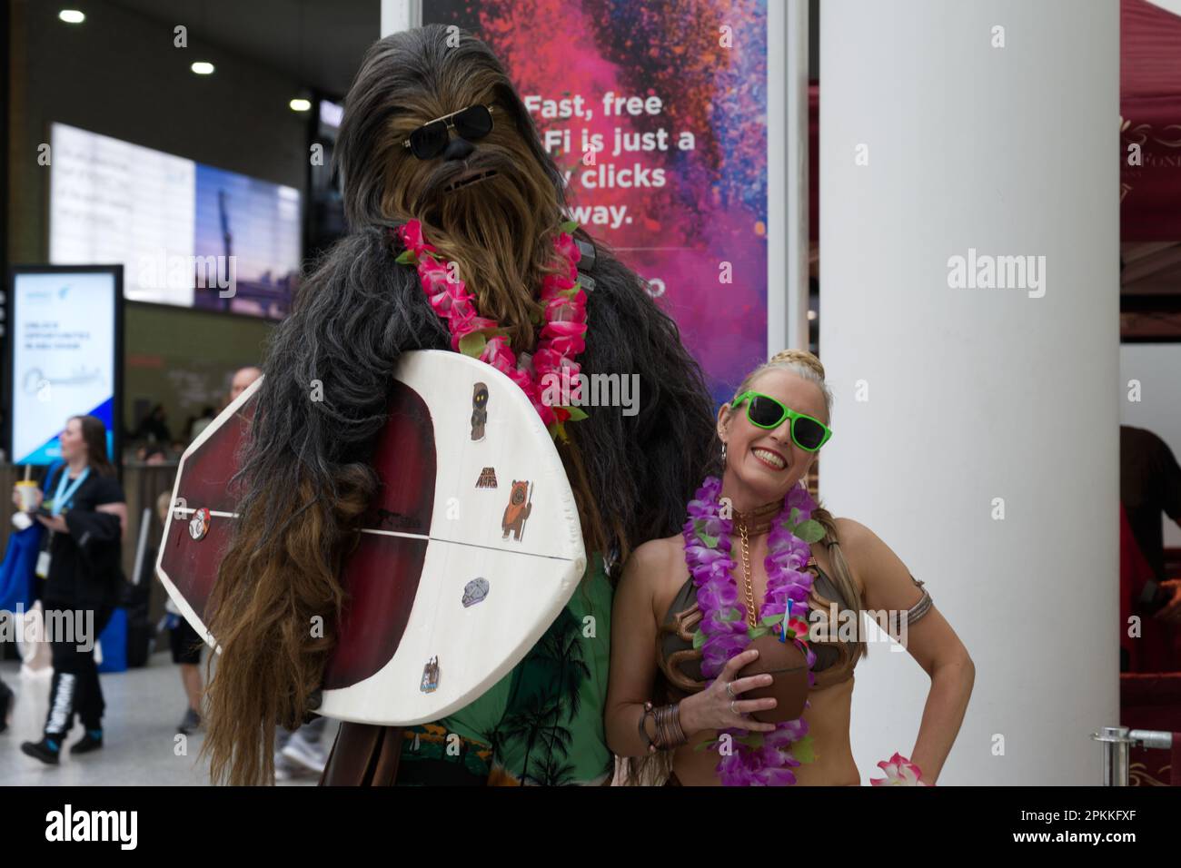 Chewbacca carrying a surfboard and a woman in a Princess Leia bikini at the Star Wars Celebration 2023 Stock Photo