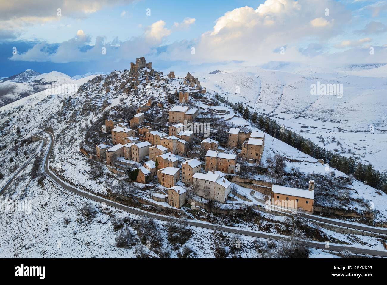 Aerial winter view of the snow covered medieval village of Rocca Calascio with the castle surrounded by clouds at dusk, Rocca Calascio Stock Photo