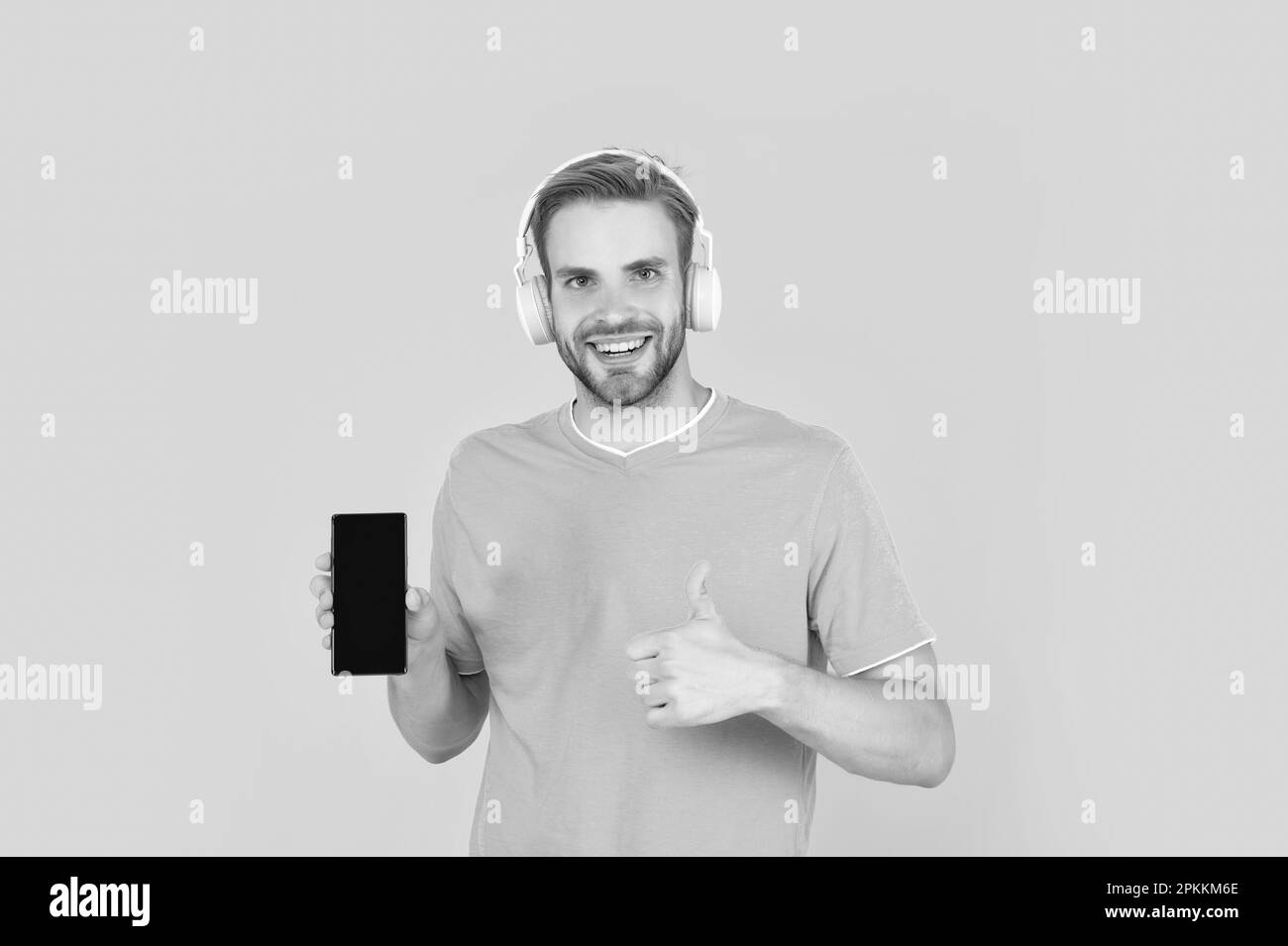 The best phone. Happy guy give thumbs up to mobile phone. Music smartphone. Listening to podcast or watching video. Use it to make you feel different. Stock Photo