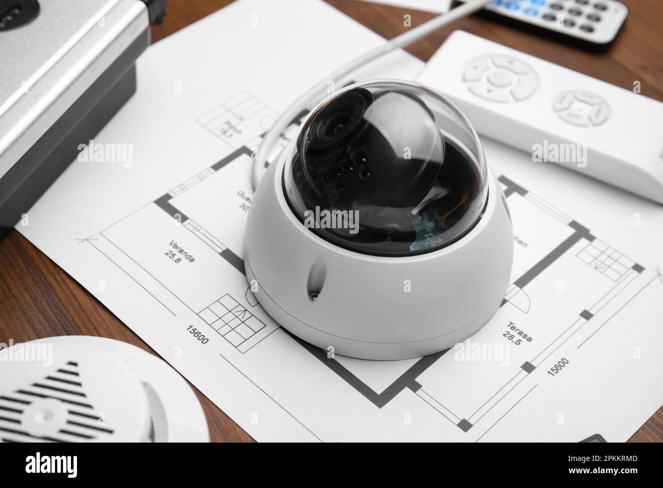 CCTV camera and building plan on wooden table, closeup. Home security