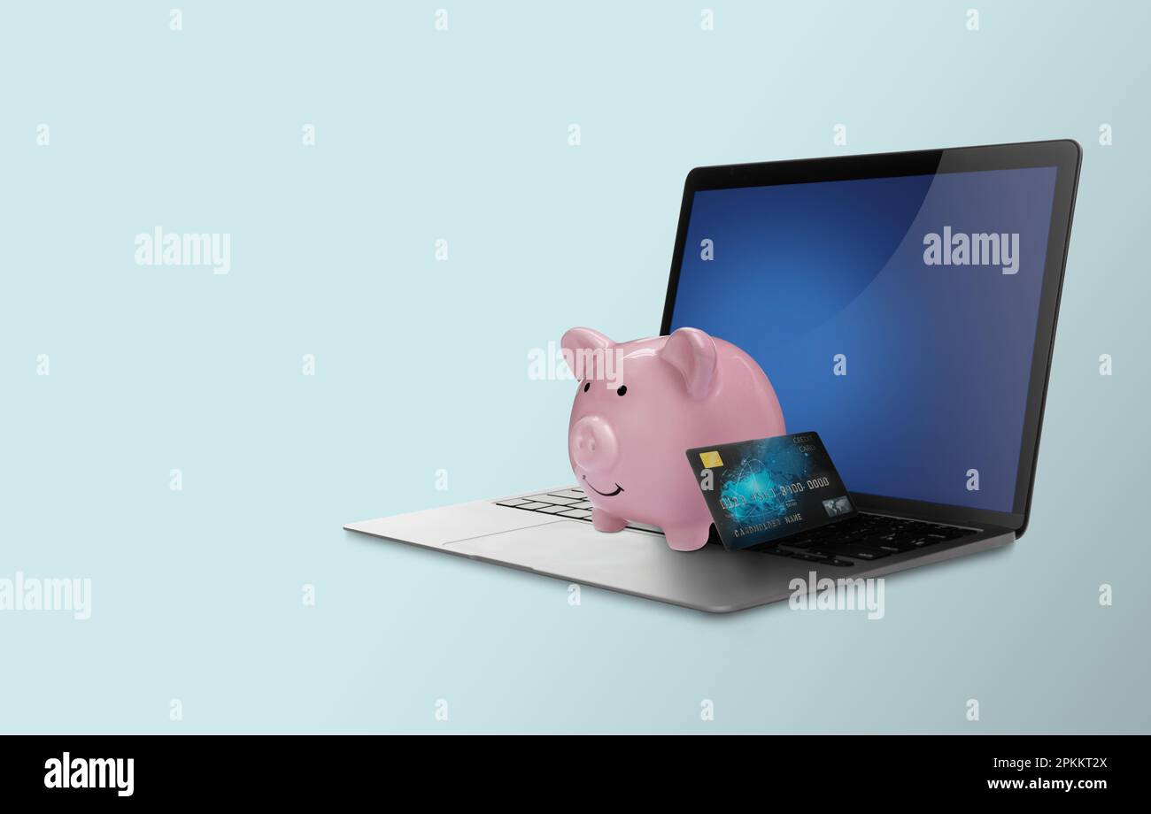 Piggy bank with credit card and laptop on light blue background. Online