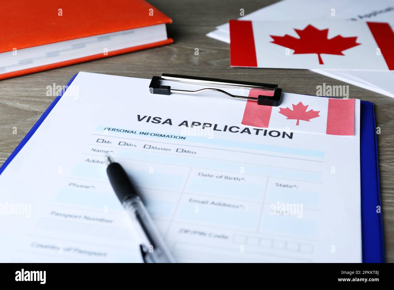 Visa application form for immigration to Canada and pen on wooden table ...