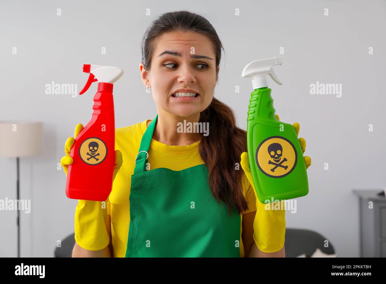 Woman showing bottles of toxic household chemical with warning signs