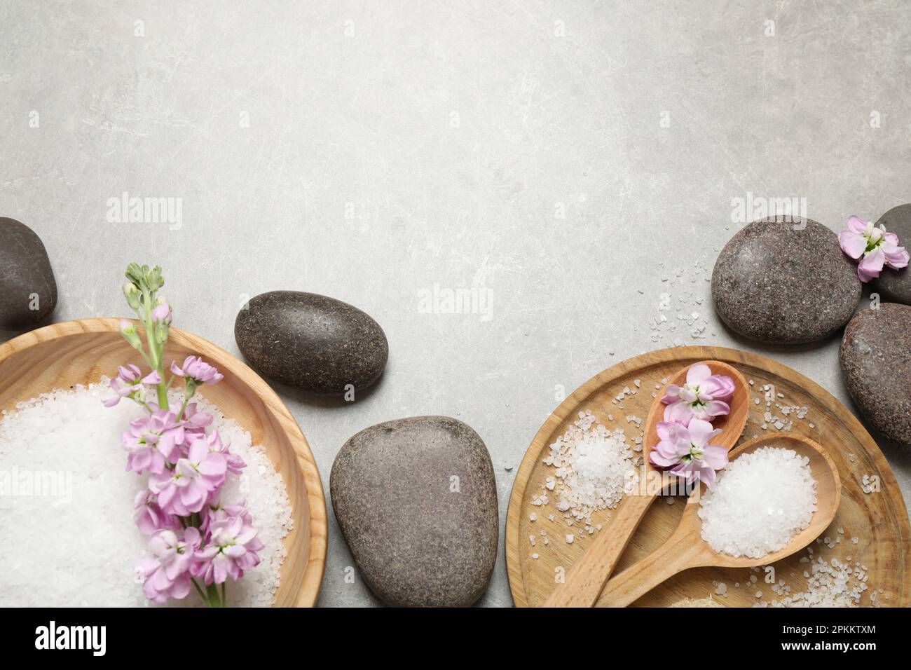 Flat lay composition with sea salt and spa stones on grey marble table ...