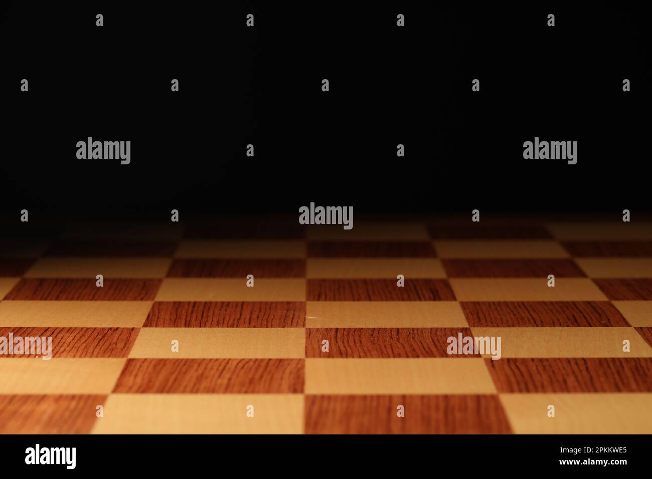 Checkered chessboard on dark background, closeup view Stock Photo