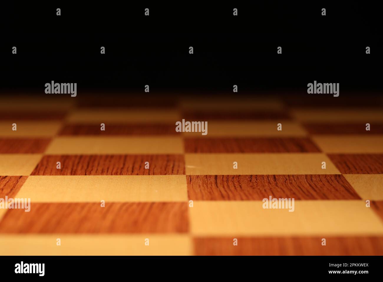 Checkered chessboard on dark background, closeup view Stock Photo