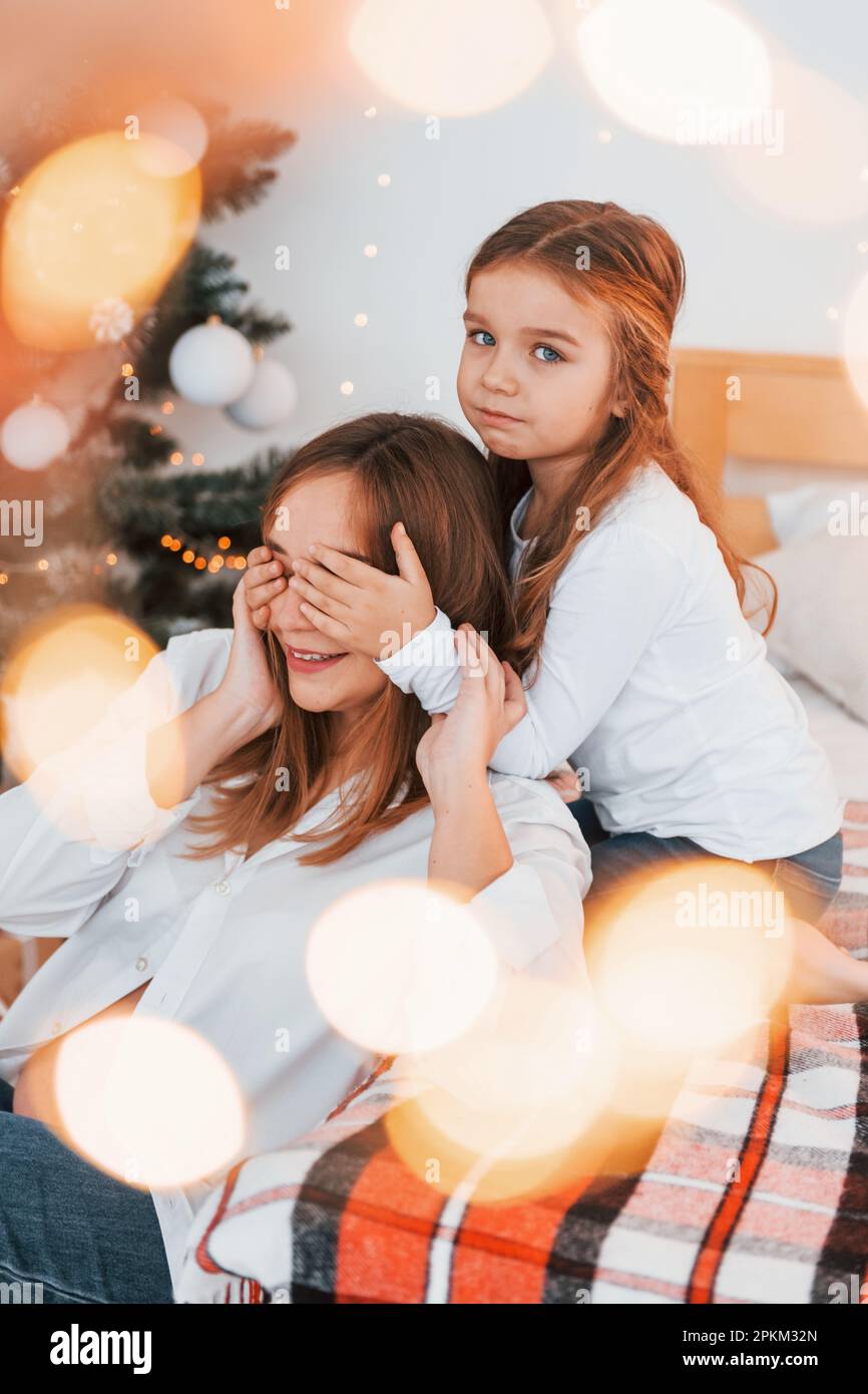 Having fun. Mother with her little daughter is having fun indoors on the bed. Stock Photo