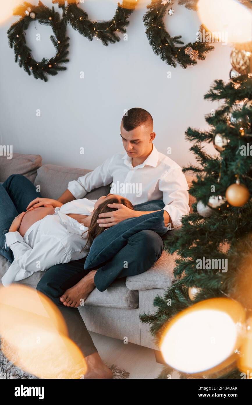 Woman is pregnant. Lovely couple celebrating holidays together indoors. Stock Photo