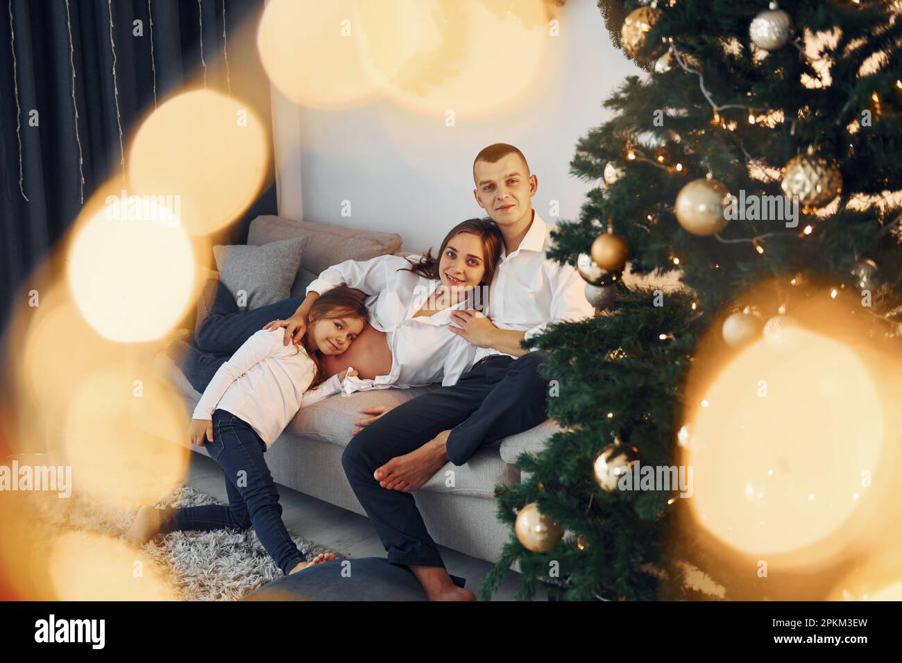With Christmas tree. Happy family celebrating holidays indoors together. Stock Photo