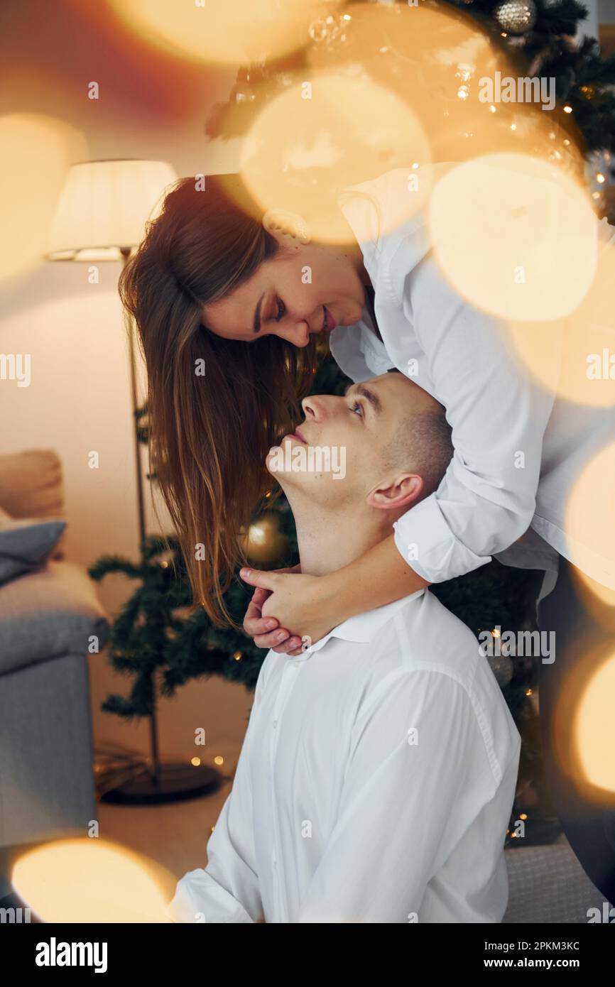 Embracing each other. Lovely couple celebrating holidays together indoors. Stock Photo