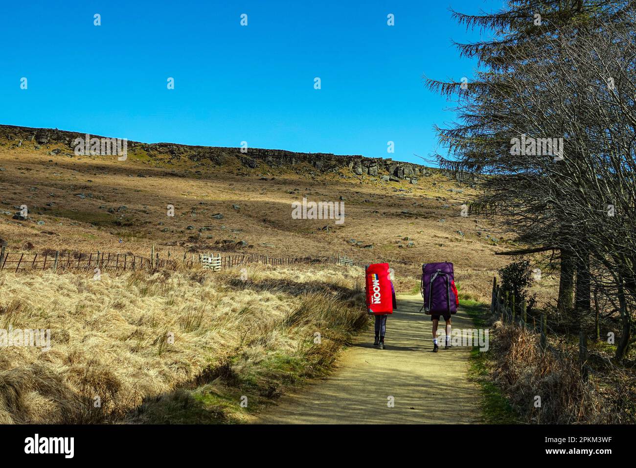 Two climbers with bouldering mats, pads, approaching Stanage Edge, a