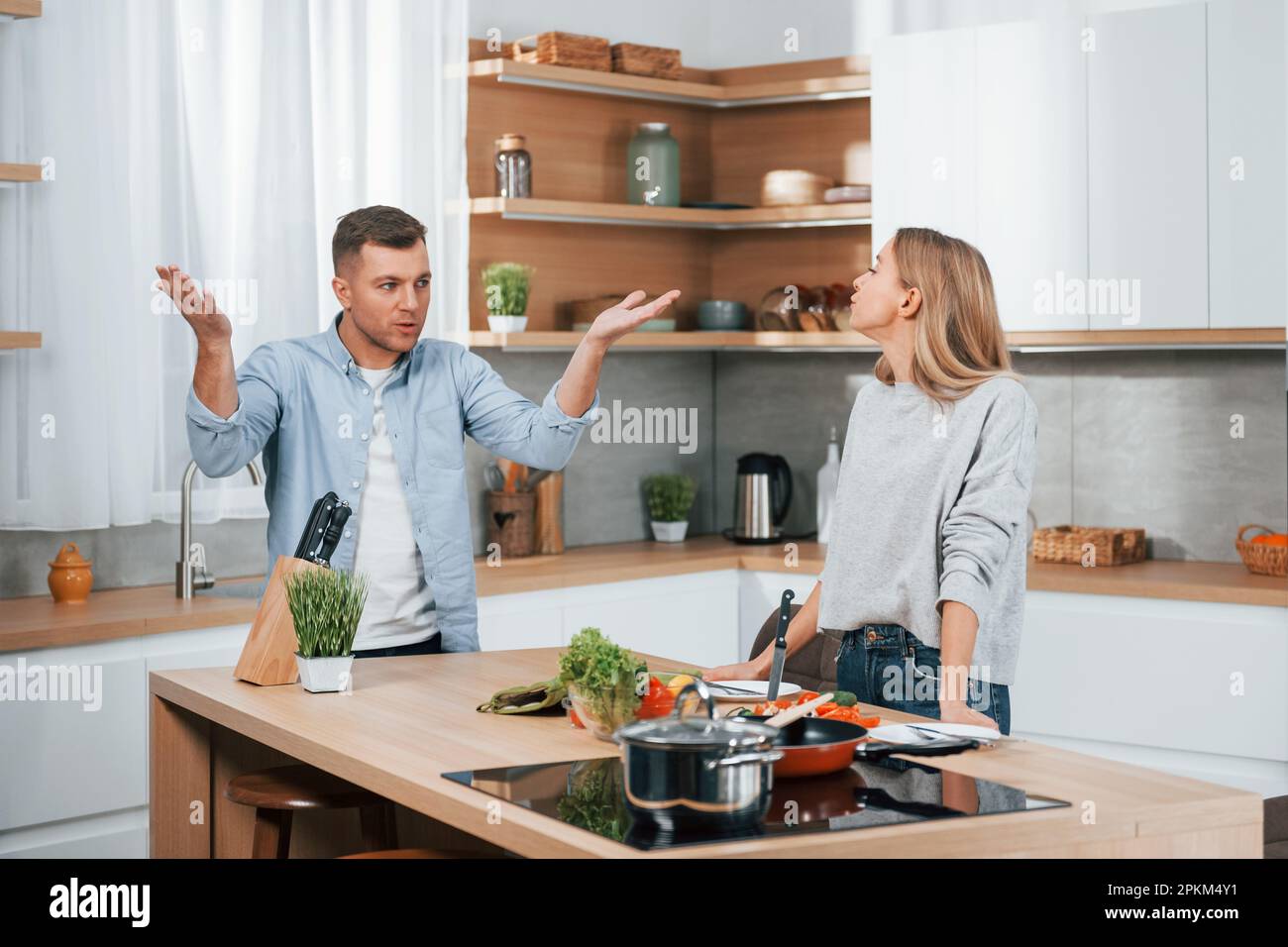 Screaming and arguing with each other. Couple preparing food at home on the modern kitchen. Stock Photo
