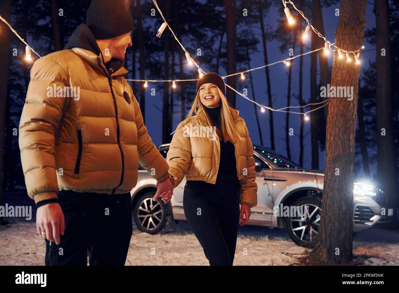 Automobile parked behind. Couple standing in the forest and celebrating New year. Stock Photo