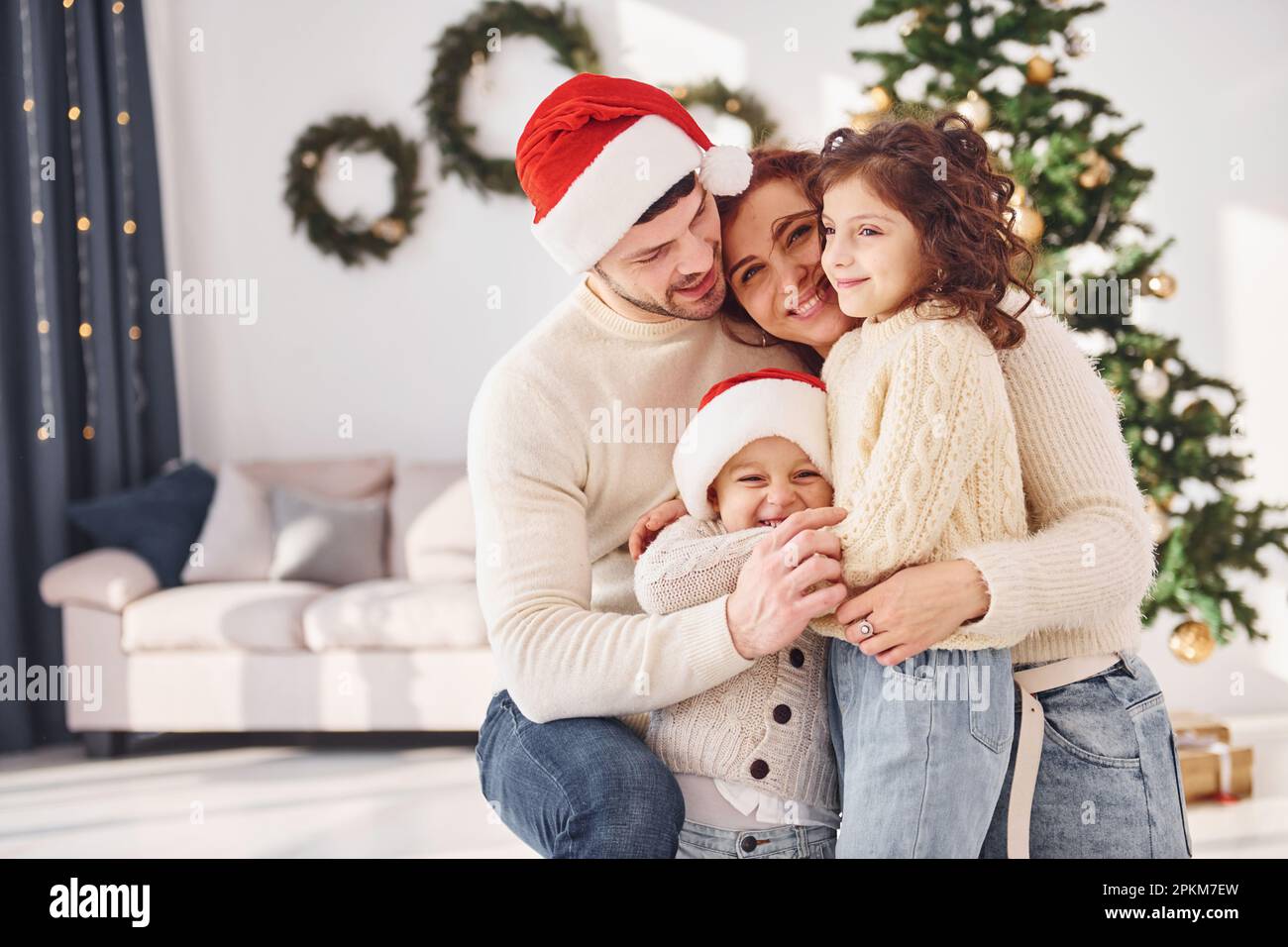 In christmas hats. Family celebrating new year with their children at home. Stock Photo