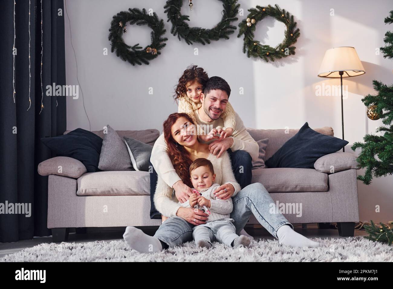 Sitting near sofa. Family celebrating new year with their children at home. Stock Photo