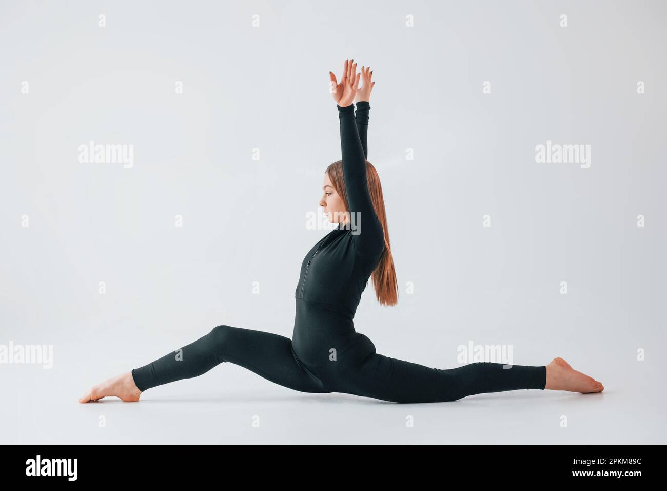 Side stretch. Young woman in sportive clothes doing gymnastics indoors. Stock Photo