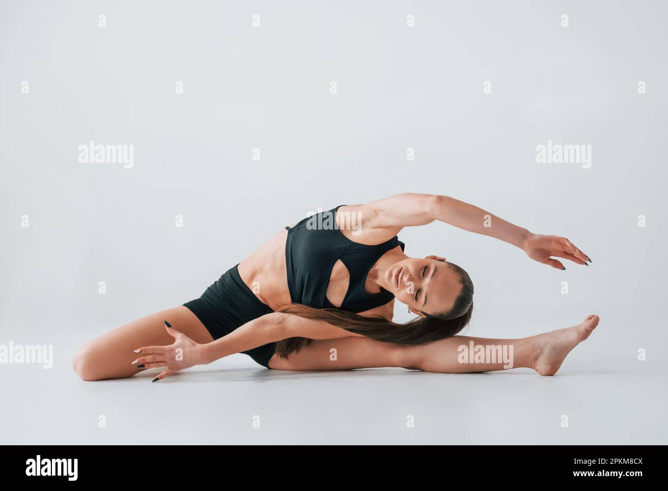 Focused on the exercises. Young woman in sportive clothes doing gymnastics indoors. Stock Photo