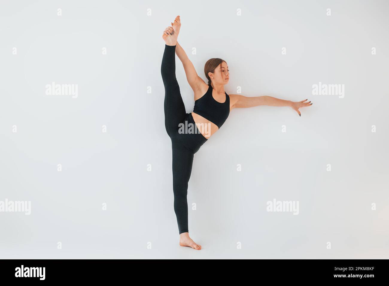 Exercises for the legs. Young woman in sportive clothes doing gymnastics indoors. Stock Photo