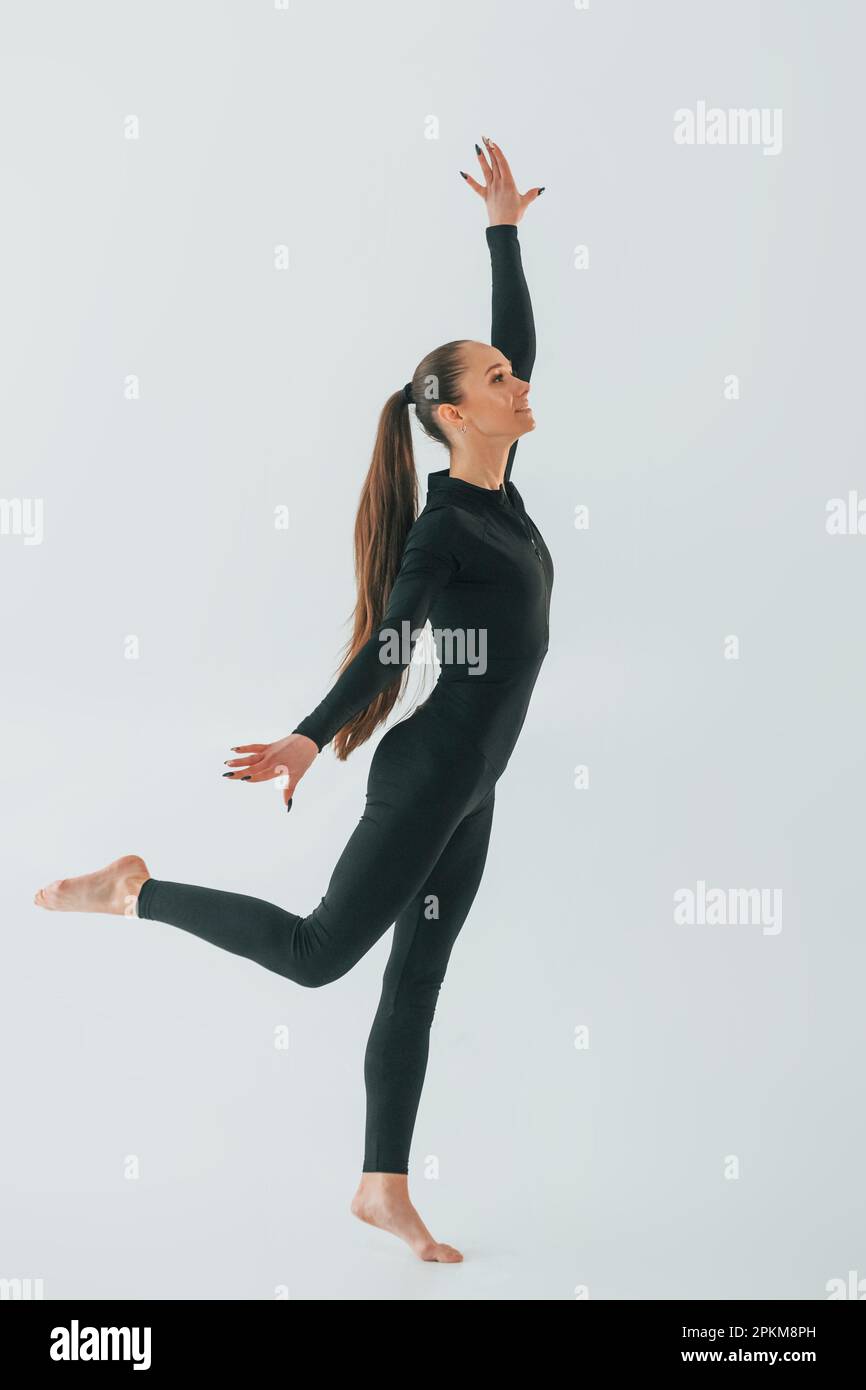 In black sportive clothes. Young woman doing gymnastics indoors. Stock Photo