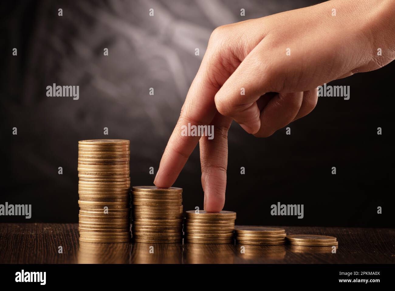 Finger stepping on coin stack, profit making concept Stock Photo - Alamy