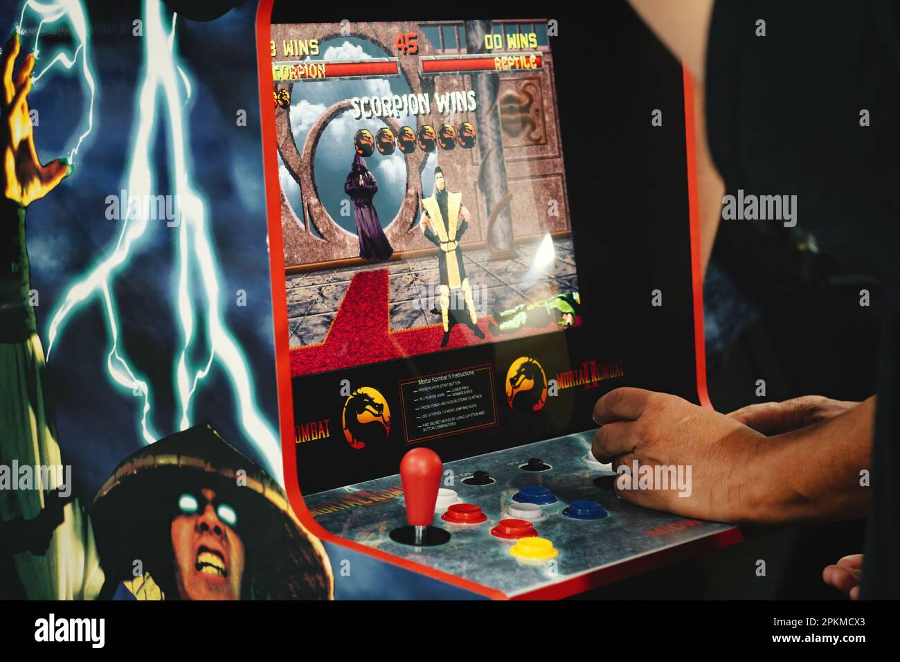 Close-up of an old retro gaming arcade game - Mortal Kombat II, with a man's hands on the cabinet control panel Stock Photo