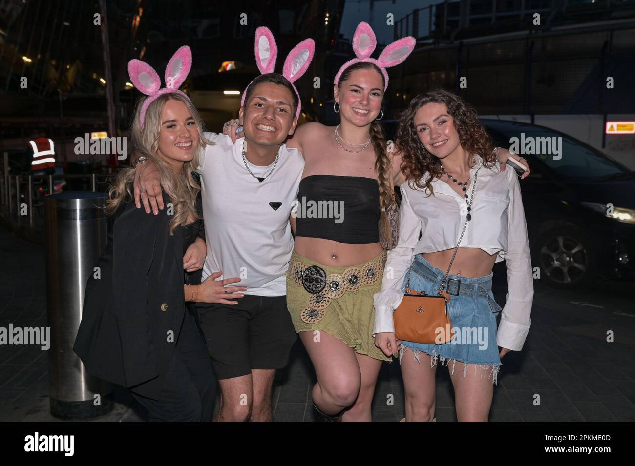 Birmingham city centre, 8th April 2023 - Revellers hit the town in Birmingham early on Saturday evening to continue the Easter Bank Holiday. Many of the party-goers wore pink and bunny ears whilst some swigged from a bottle of Lambrini. Ladies posed for a photo along with bouncers from Dirty Martini who expect Saturday to be a bumper night. Credit: Katie Stewart/Alamy Live News Stock Photo