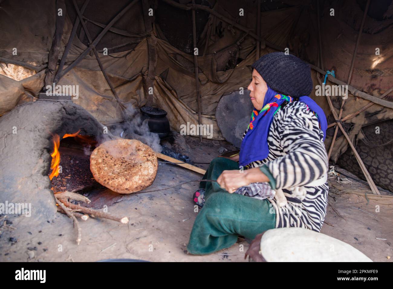 A Moroccan woman cooks a berber pizza in a wood burning oven Stock Photo