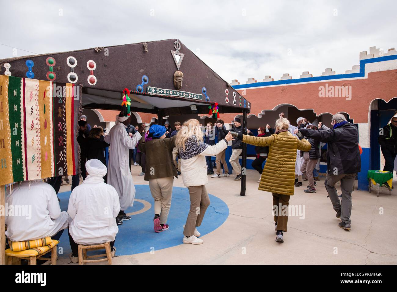 A group of tourists dance with local men at the Dar Gnaoua Bambara Khamlia Cultural Center Stock Photo