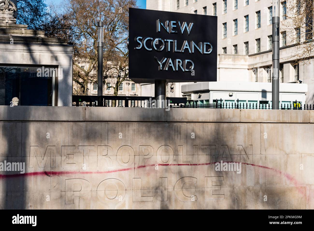 Vandalised sign outside New Scotland Yard building, headquarters of the Metropolitan Police, on the Victoria Embankment, London, UK. Red paint line Stock Photo