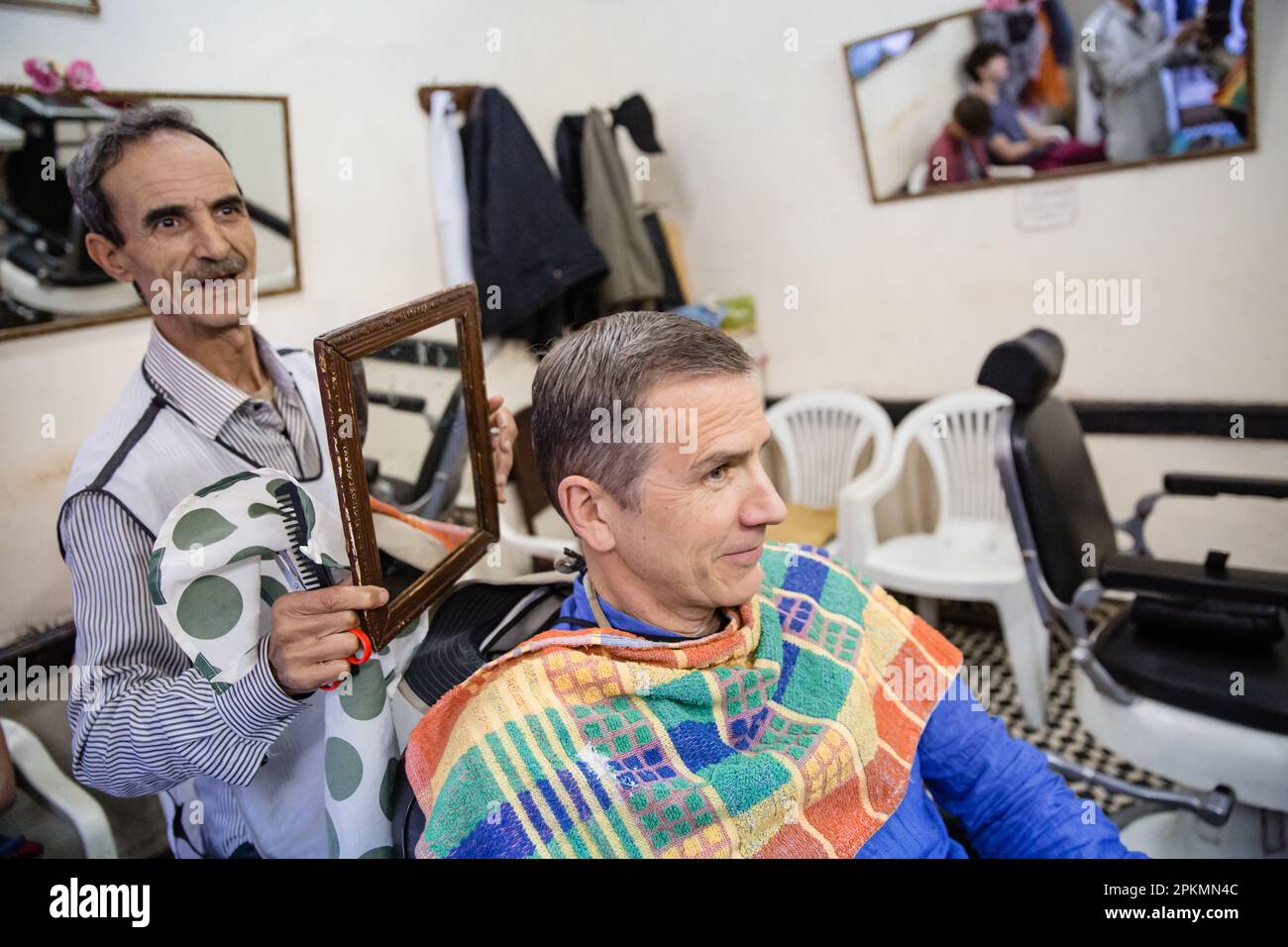 An American tourist looks in a mirror after getting a straight razor shave and a haircut in a barbershop in Marrakech Morocco Stock Photo
