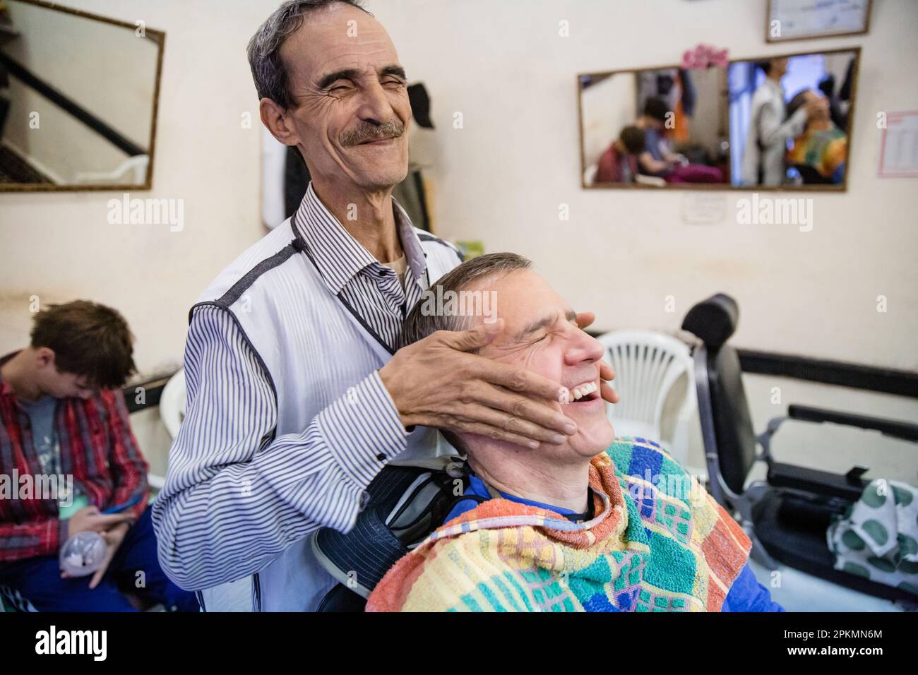 An American tourist getting a straight razor shave and a haircut in a barbershop in Marrakech Morocco Stock Photo