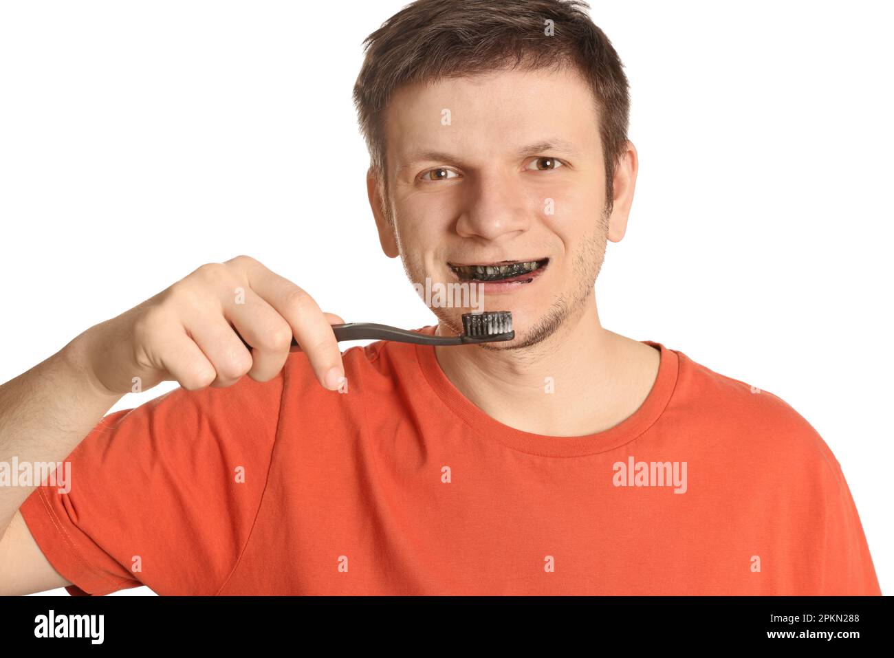 Man brushing teeth with charcoal toothpaste on white background Stock