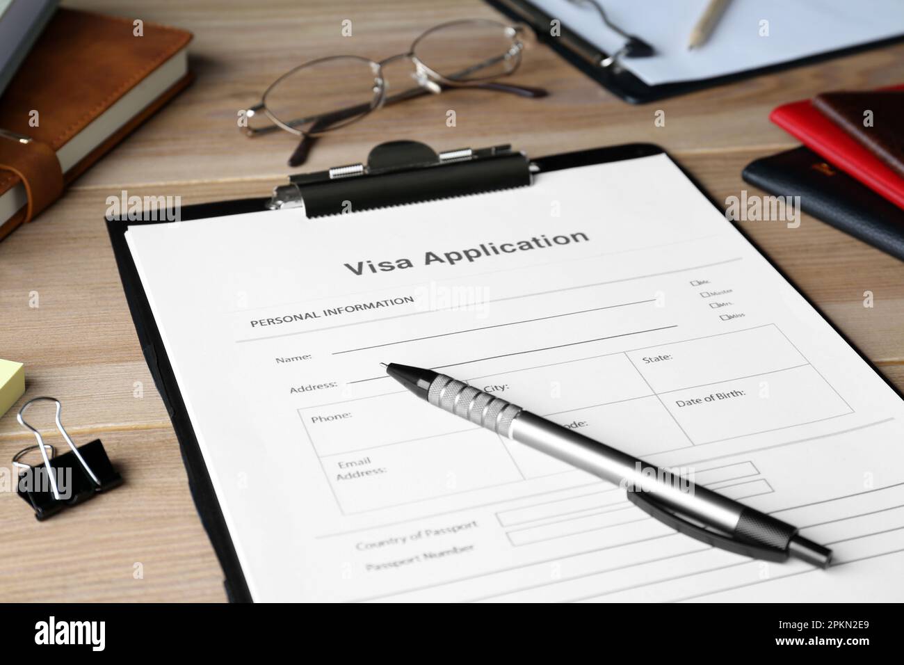 Visa application form for immigration and stationery on wooden table, closeup Stock Photo