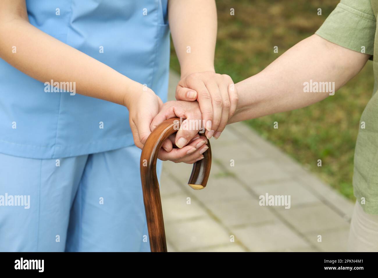 Elderly woman with walking cane and female caregiver outdoors, closeup Stock Photo